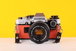 Olympus OM10 35mm SLR Film Camera With Manual Adapter And Olympus Zuiko Auto-S 50mm F1.8 Lens In Orange